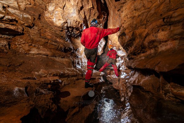 Deux spéléo se suivent en passant en hauteur sur des banquettes (Grotte de Pézenas, Ardèche)