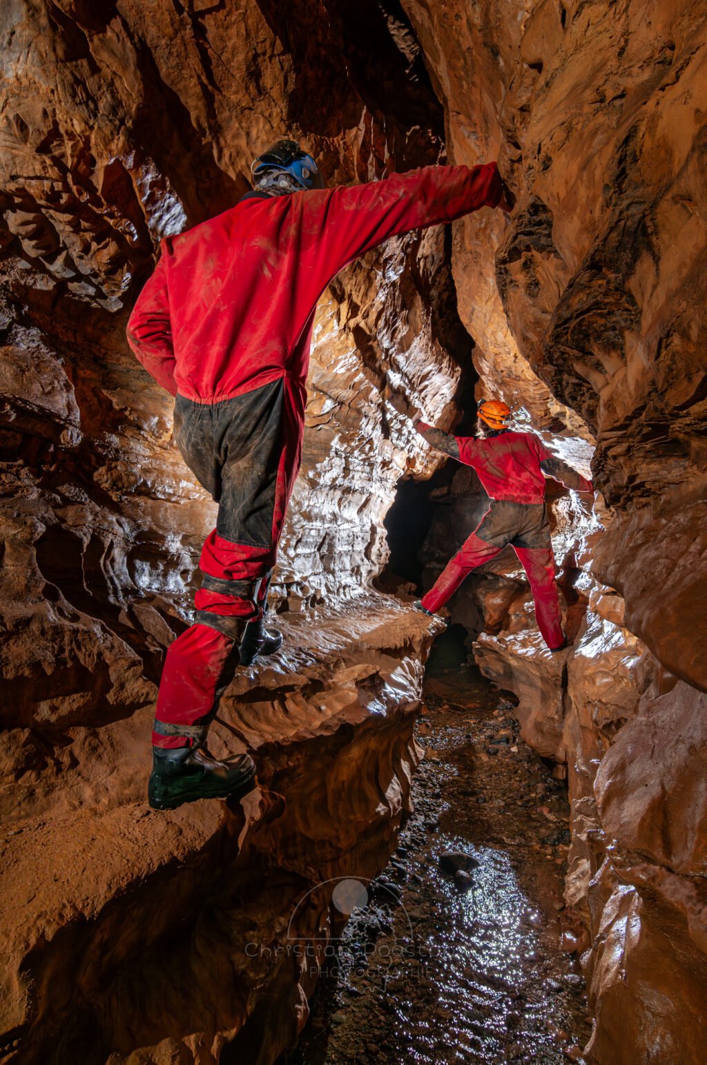 Deux spéléo se suivent en passant en hauteur sur des banquettes (Grotte de Pézenas, Ardèche)