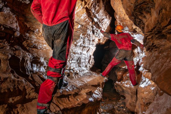 Deux spéléo se suivent en passant en hauteur sur des banquettes (Grotte de Pézenas, Ardèche)