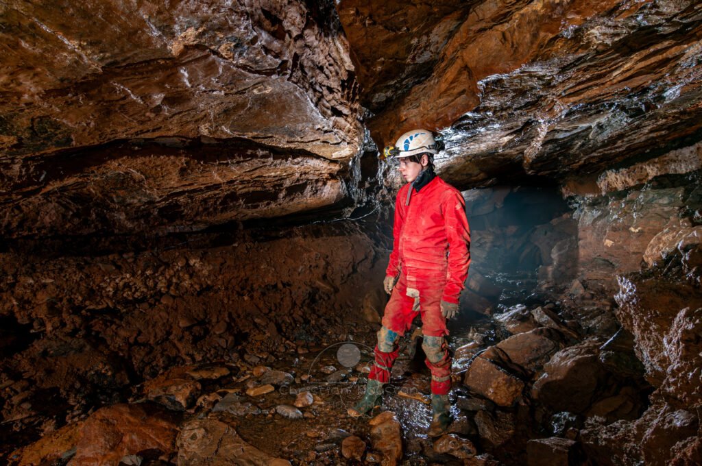 Spéléo dans la galerie, on remarque la ligne pour le téléphone qui court le long de la paroi. (Grotte de Pézenas, Ardèche)