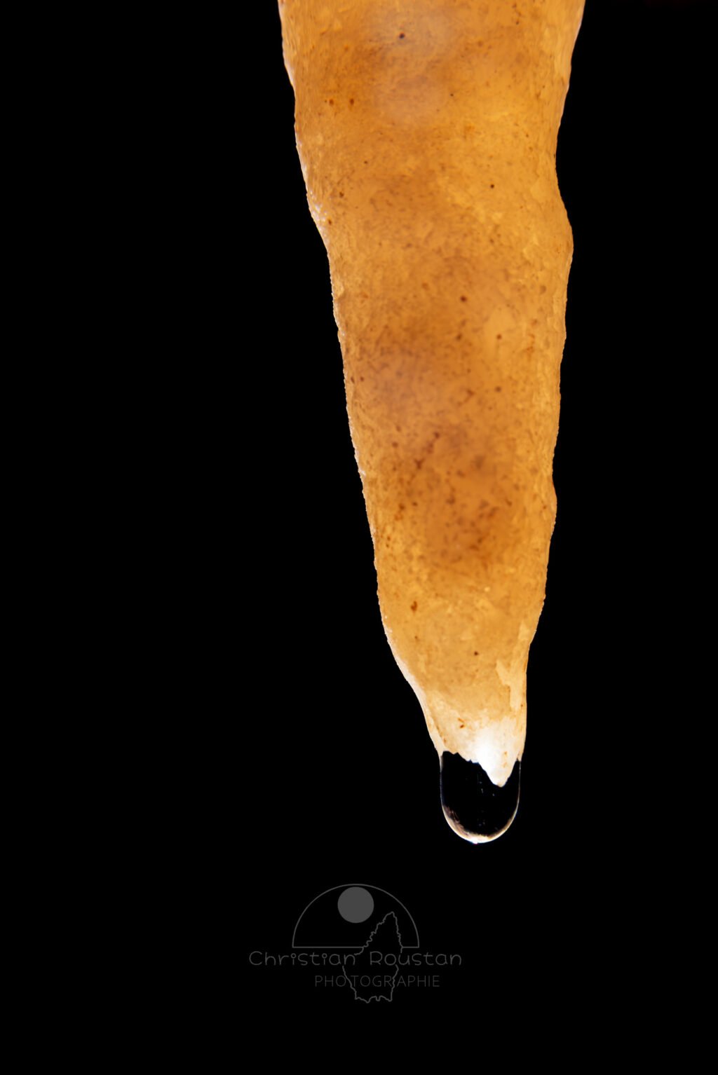 Une goutte d'eau à l’extrémité d'une stalactite (Spéléothème, Grotte du Philosophe, Gard)