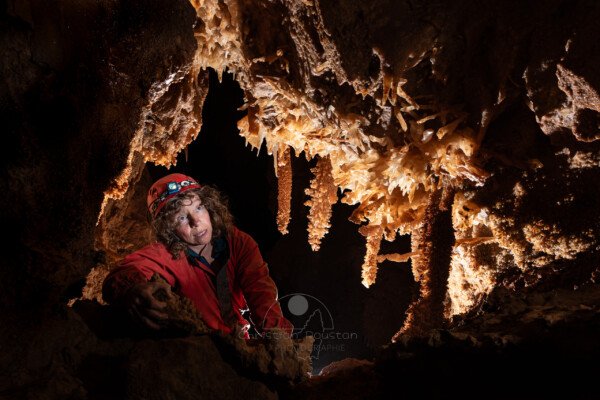 Spéléologue dans une lucarne richement concrétionnée (Spéléothème, Grotte du Philosophe, Gard)