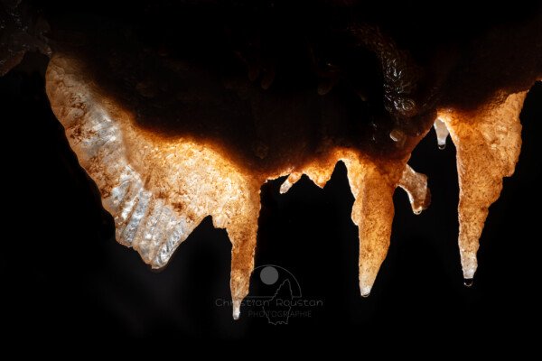 Trio de concrétions éclairées par transparence pour bien voir la structure cristalline (Spéléothème, Grotte du Philosophe, Gard)