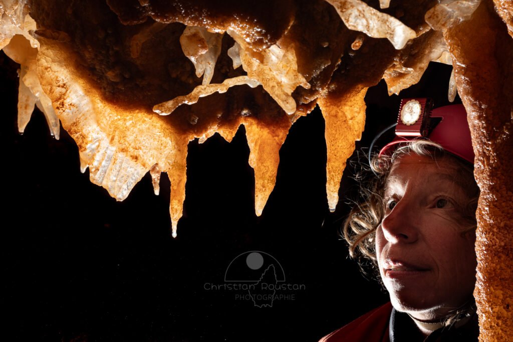 Spéléologue regardant trois concrétions au plafond (Spéléothème, Grotte du Philosophe, Gard)