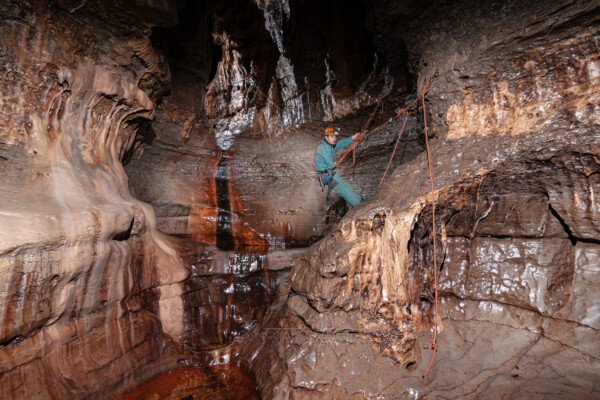 Passage de la main courante au dessus de la grande vasque (Spéléo, Goule de Sauvas, Ardèche)