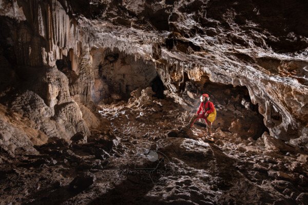 Un spéléo au centre face aux grands massifs de concrétions (Spéléo, Grotte du Prevel, Gard)