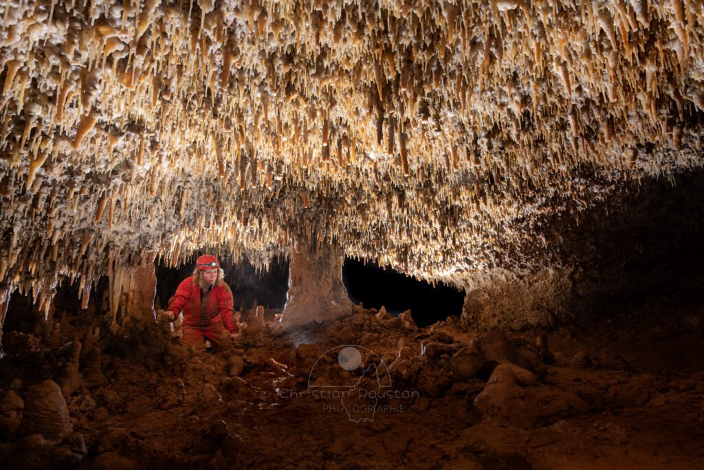 Spéléo dans passage bas, la plafond est couvert de petites stalactites.(Spéléo, Grotte du Prevel, Gard)