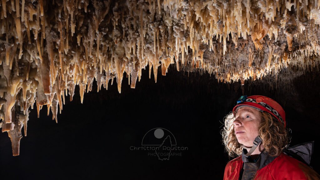 Spéléo qui regarde le plafond richement concrétionné (Spéléo, Grotte du Prevel, Gard)