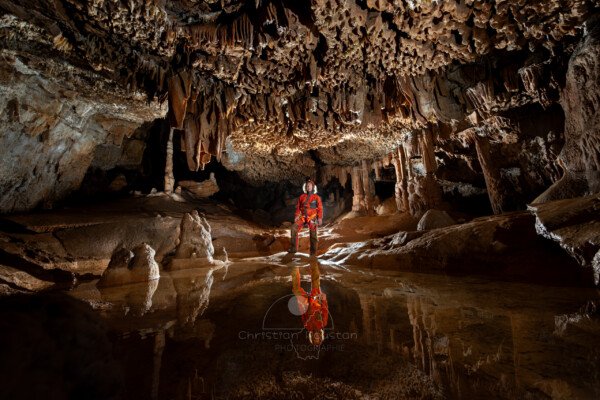 Spéléo avec son reflet dans la salle du lapiaz de voûte (Spéléo, Grotte du Ranc Chabrier, Gard)