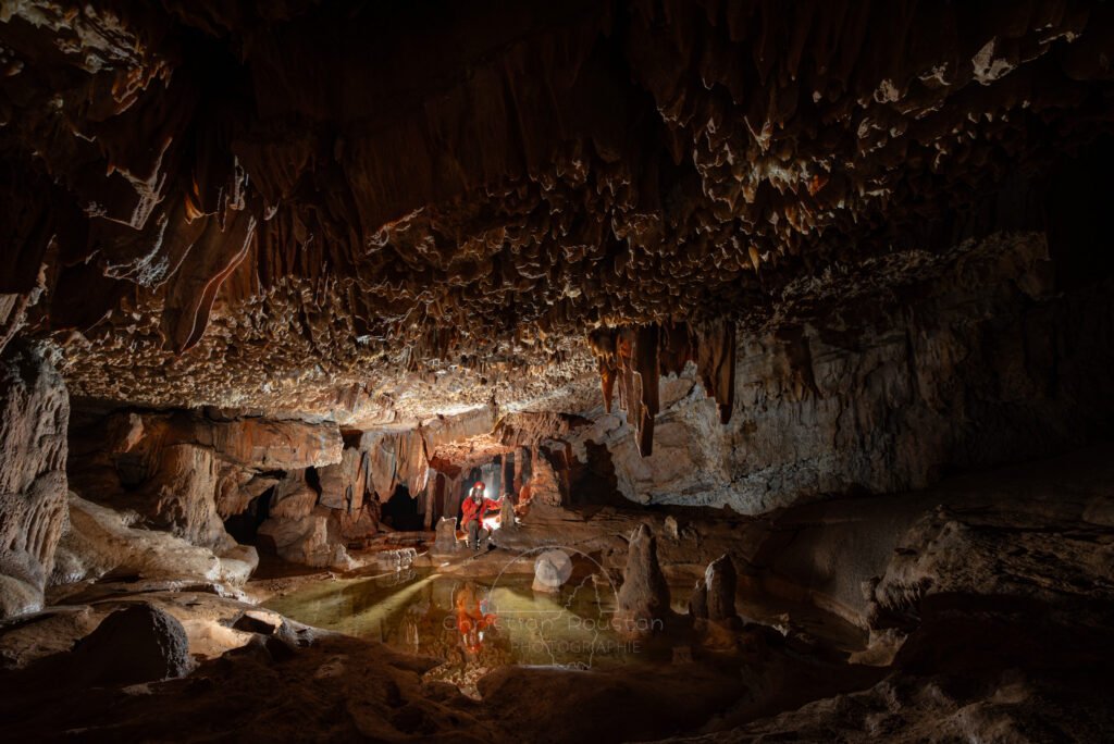 Spéléo avec son reflet dans la salle du lapiaz de voûte (Spéléo, Grotte du Ranc Chabrier, Gard)